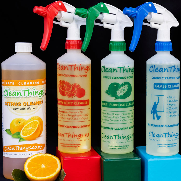Citrus Cleaner 1 litre concentrate beside red, green and blue spray bottles on matching blocks, with an orange half